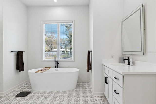 bathroom featuring a freestanding tub, vanity, and baseboards