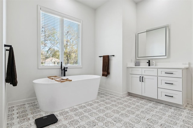 full bath with a soaking tub, vanity, and baseboards