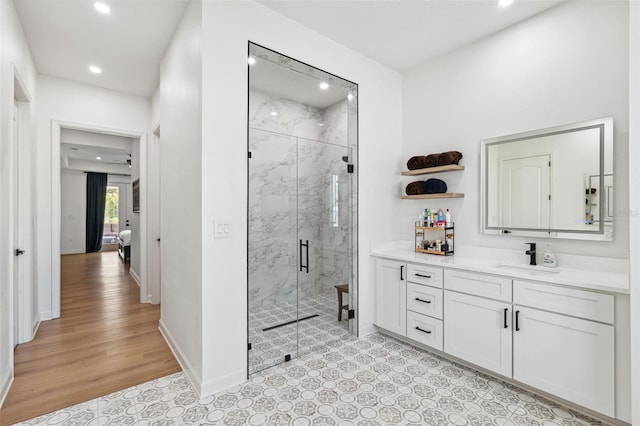 full bathroom featuring recessed lighting, wood finished floors, vanity, baseboards, and a marble finish shower