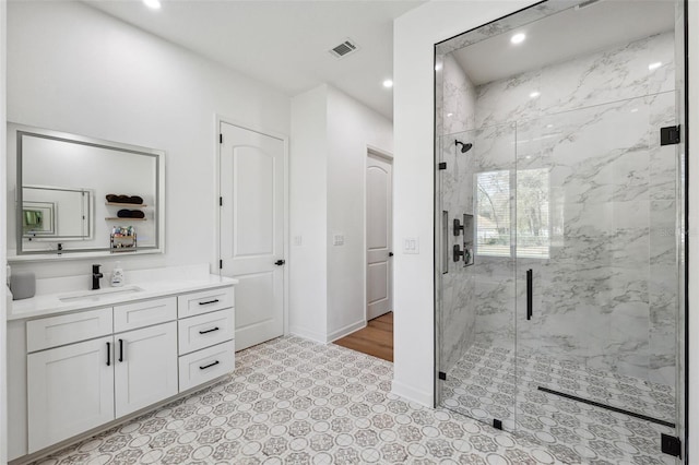 bathroom featuring vanity, a marble finish shower, visible vents, and baseboards