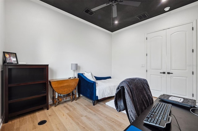 bedroom with a closet, wood finished floors, visible vents, and crown molding