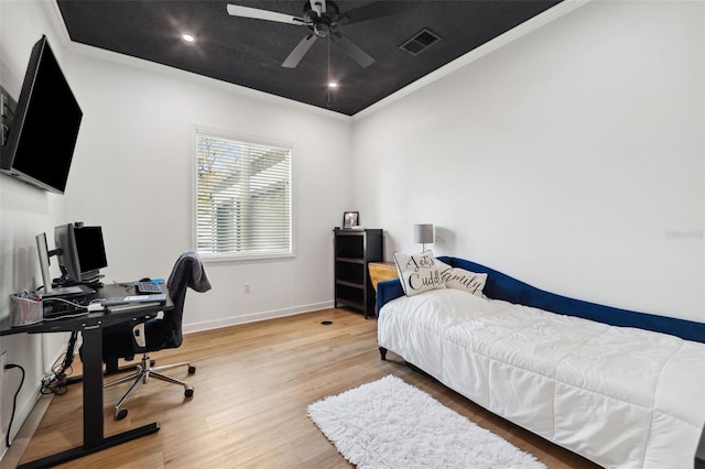 bedroom featuring baseboards, visible vents, wood finished floors, and ornamental molding