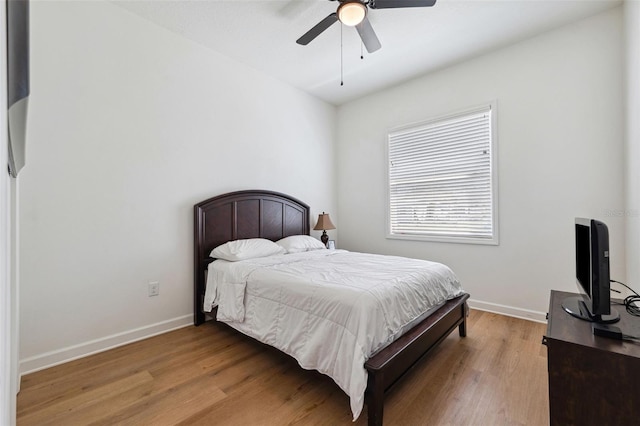 bedroom featuring light wood-type flooring, baseboards, and a ceiling fan