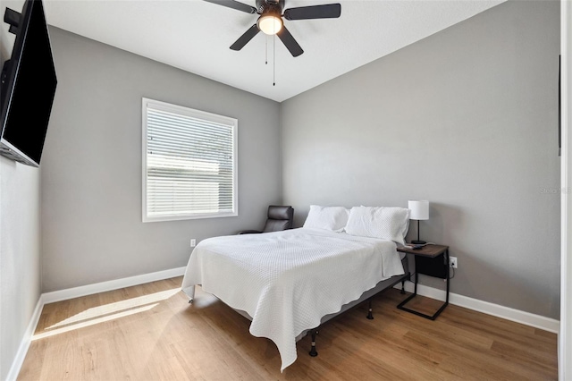 bedroom with a ceiling fan, baseboards, and wood finished floors