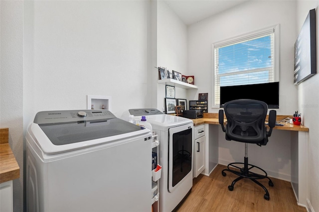 clothes washing area featuring cabinet space, light wood finished floors, and washing machine and clothes dryer