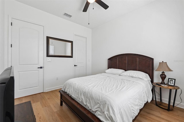 bedroom featuring a ceiling fan, visible vents, light wood-style flooring, and baseboards