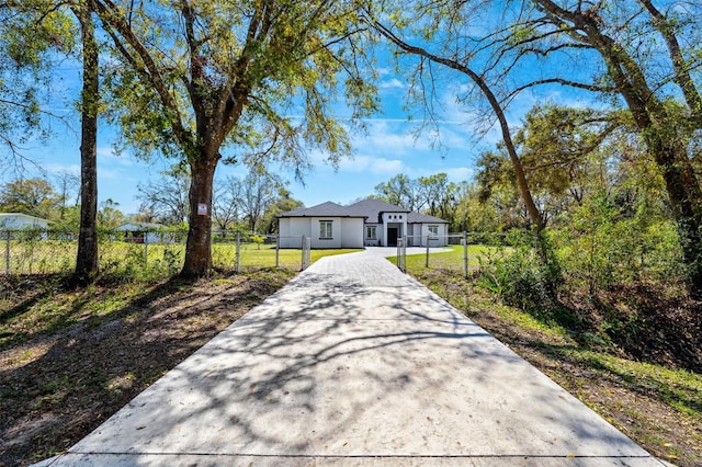 view of front of home with a fenced front yard, a front yard, concrete driveway, and a gate