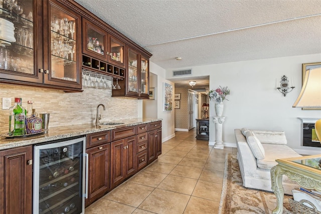 634 Edgewater Dr Unit 744, Dunedin, FL 34698 - indoor wet bar with beverage cooler, light tile patterned flooring, decorative backsplash, and a textured ceiling