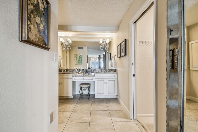 634 Edgewater Dr Unit 744, Dunedin, FL 34698 - bathroom with a chandelier, tile patterned floors, double vanity, and a textured ceiling