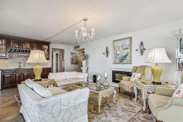 634 Edgewater Dr Unit 744, Dunedin, FL 34698 - living room featuring a textured ceiling, bar with sink, a chandelier, and a glass covered fireplace