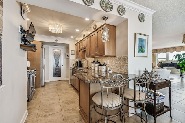634 Edgewater Dr Unit 744, Dunedin, FL 34698 - kitchen with appliances with stainless steel finishes, brown cabinetry, a peninsula, a breakfast bar area, and light tile patterned floors