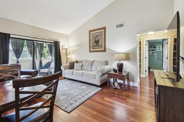 living room featuring high vaulted ceiling, visible vents, baseboards, and hardwood / wood-style flooring