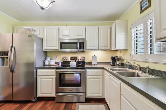 kitchen featuring stainless steel appliances, dark wood-type flooring, a sink, white cabinetry, and dark countertops