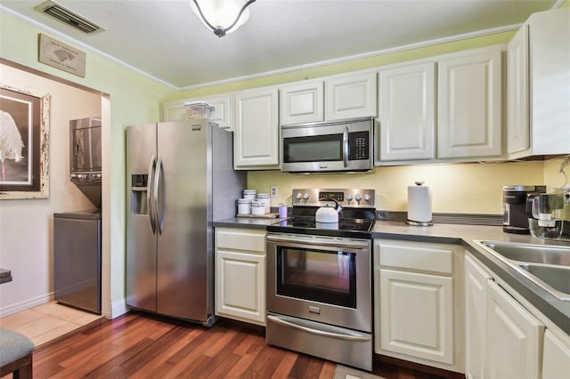 kitchen with crown molding, stainless steel appliances, visible vents, dark wood-type flooring, and white cabinets