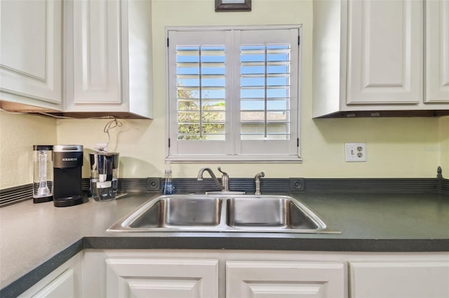 kitchen featuring dark countertops, a sink, and white cabinets