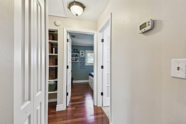 corridor featuring baseboards and dark wood-style flooring