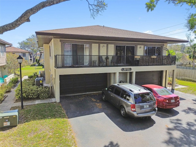 view of front of home with a garage, aphalt driveway, central AC unit, and stucco siding