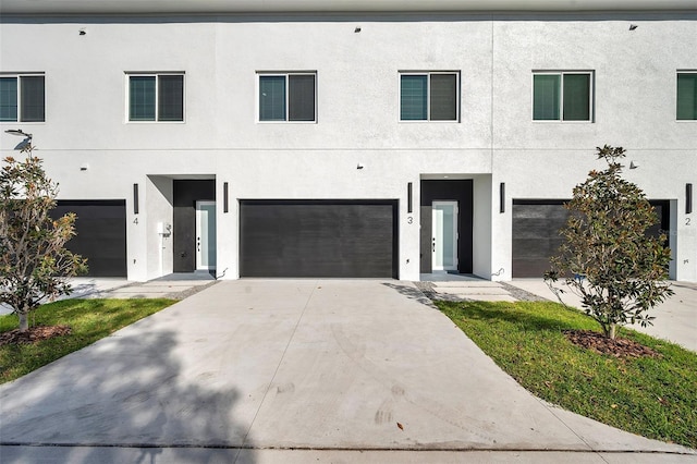 view of front facade featuring an attached garage, concrete driveway, and stucco siding