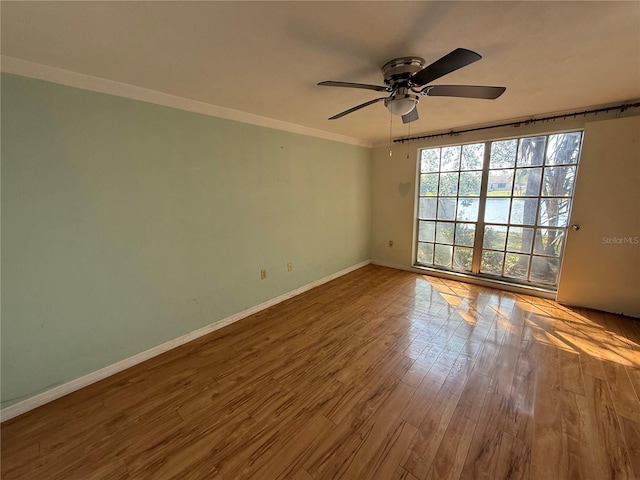 empty room featuring baseboards, wood finished floors, a ceiling fan, and ornamental molding