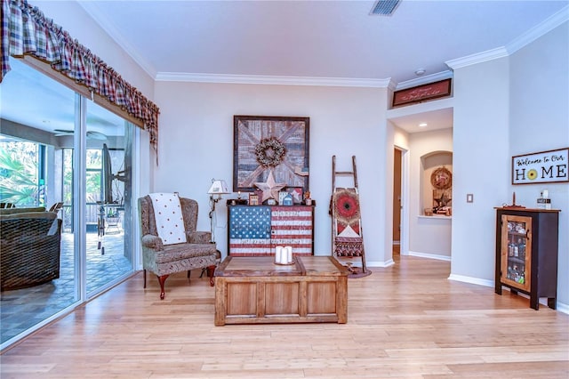 sitting room featuring light wood-style flooring, arched walkways, and crown molding