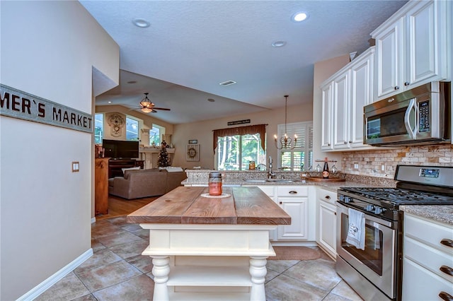 kitchen with stainless steel appliances, a peninsula, a sink, white cabinetry, and open floor plan