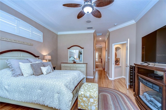 bedroom featuring light wood-style floors, baseboards, visible vents, and ornamental molding