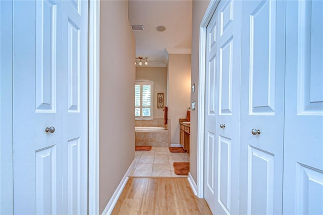 corridor featuring light tile patterned floors, baseboards, and ornamental molding