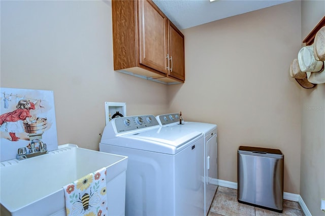 laundry room with cabinet space, a sink, baseboards, and separate washer and dryer