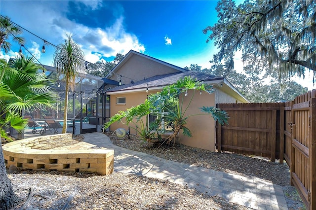 view of property exterior with a lanai, a patio area, fence, and stucco siding