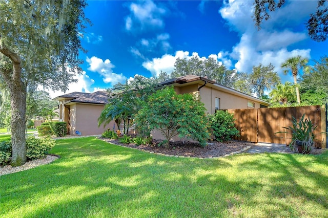 exterior space with a front yard, fence, and stucco siding