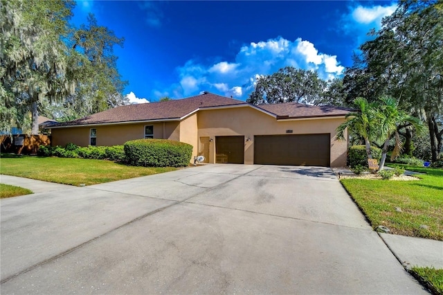 view of front of home with a garage, driveway, a front yard, and stucco siding