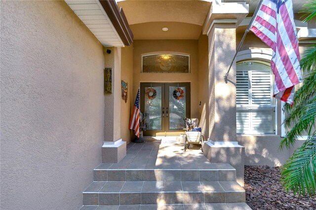 view of exterior entry featuring french doors and stucco siding