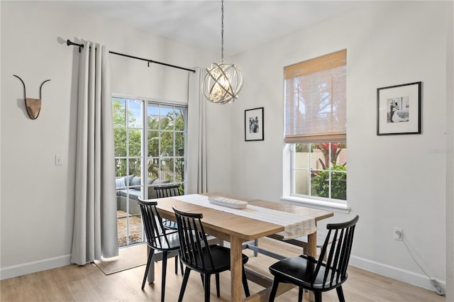 dining area featuring an inviting chandelier, light wood-style flooring, and baseboards