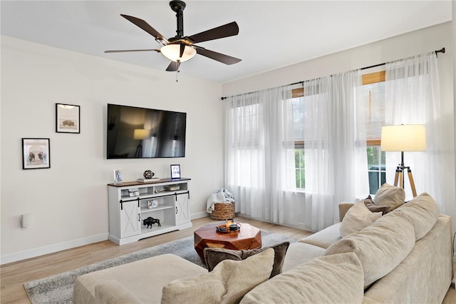 living room with light wood-style floors, ceiling fan, and baseboards