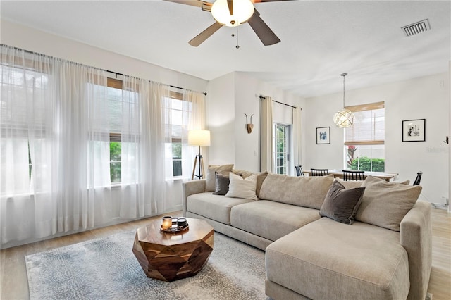 living room featuring a ceiling fan, visible vents, and wood finished floors