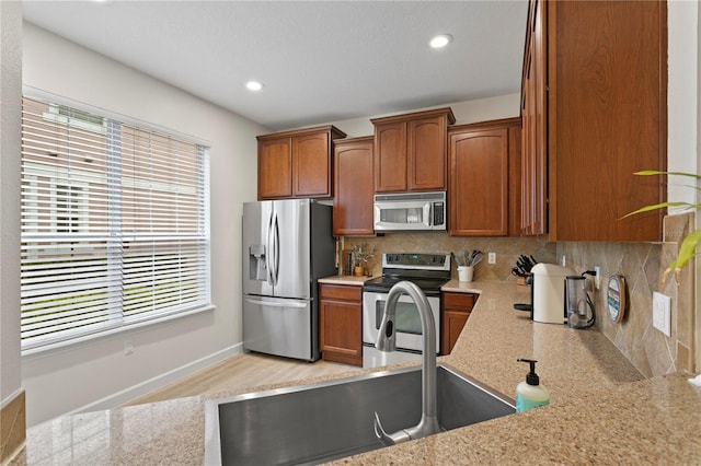 kitchen featuring stainless steel appliances, brown cabinetry, and tasteful backsplash