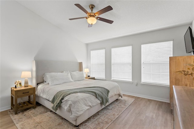 bedroom featuring vaulted ceiling, a ceiling fan, light wood-style flooring, and baseboards