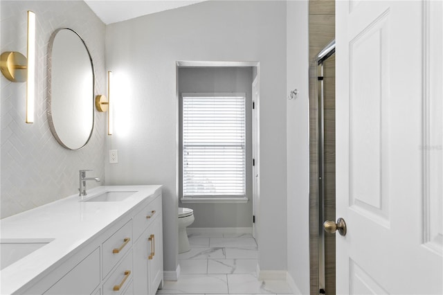 bathroom featuring double vanity, toilet, a shower with door, marble finish floor, and a sink