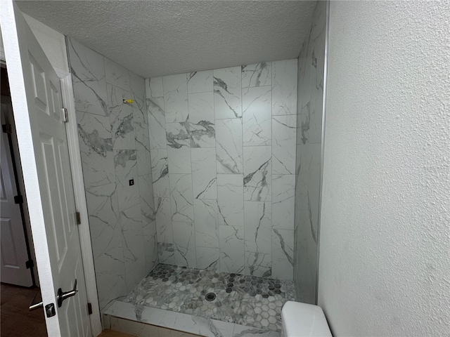 bathroom featuring toilet, a shower stall, a textured ceiling, and a textured wall