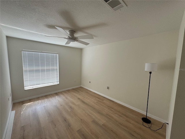 empty room featuring baseboards, visible vents, ceiling fan, wood finished floors, and a textured ceiling