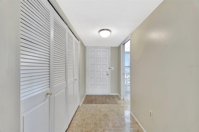 hallway featuring a textured ceiling and baseboards