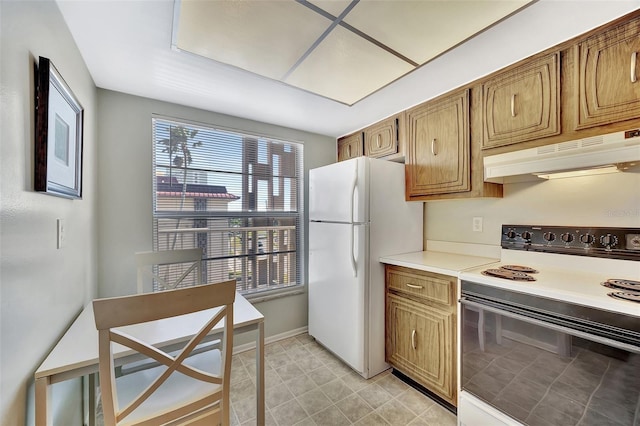 kitchen featuring under cabinet range hood, light countertops, brown cabinets, freestanding refrigerator, and electric range