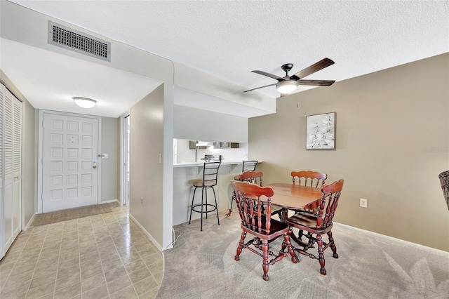 dining area with baseboards, visible vents, a textured ceiling, and ceiling fan