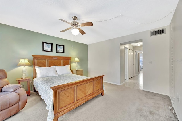 bedroom featuring visible vents, light colored carpet, a ceiling fan, and baseboards