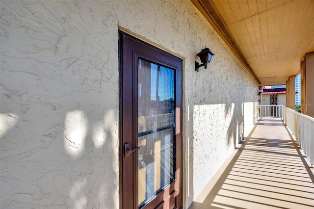 entrance to property with stucco siding and a balcony