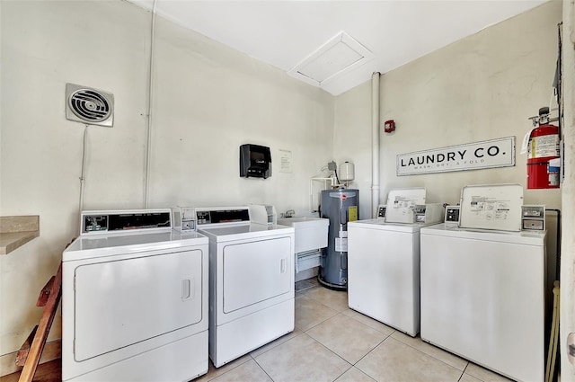 common laundry area with visible vents, electric water heater, washing machine and dryer, light tile patterned floors, and a sink