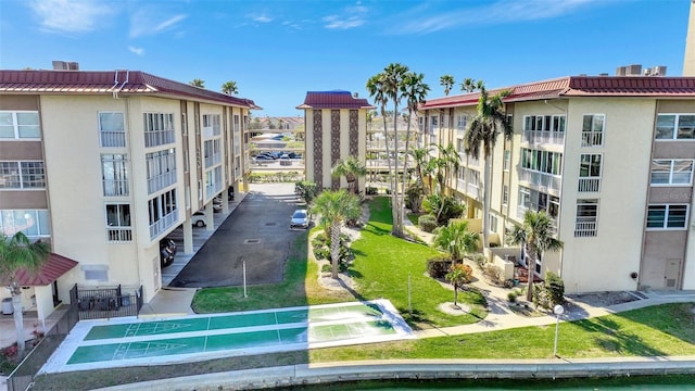 view of community featuring shuffleboard and a lawn