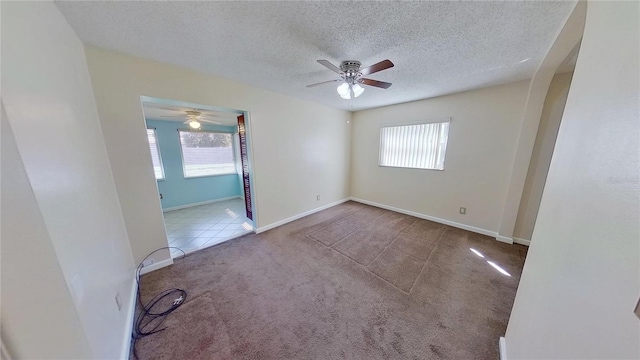 carpeted empty room with plenty of natural light, a textured ceiling, baseboards, and tile patterned floors