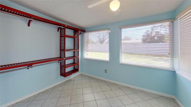 unfurnished room with a textured ceiling, a ceiling fan, and baseboards