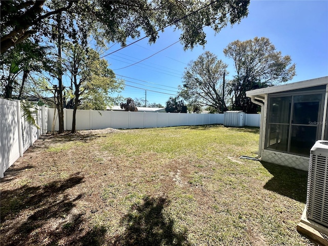 view of yard with a sunroom, a fenced backyard, and cooling unit